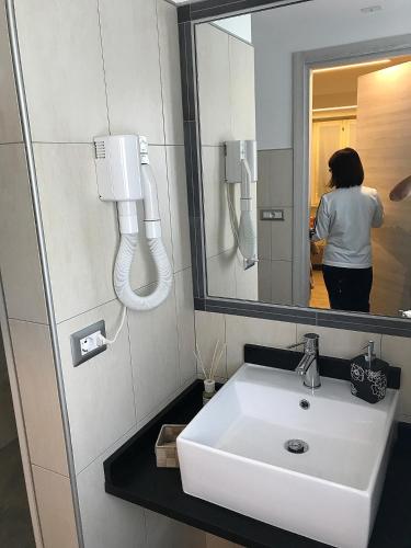 a bathroom with a sink and a person in a mirror at Casa Soave B&B in Alba