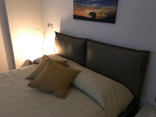 a bed with two pillows and a picture on the wall at Casa Soave B&B in Alba