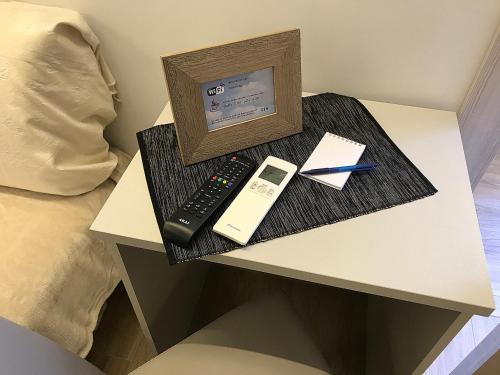 a bedside table with a remote control and a picture at Casa Soave B&B in Alba