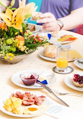 a table with plates of breakfast food and a bowl of flowers at Ringhotel Teutoburger Wald in Tecklenburg