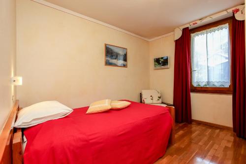 a bedroom with a red bed and a window at Albergo Adele in Bormio