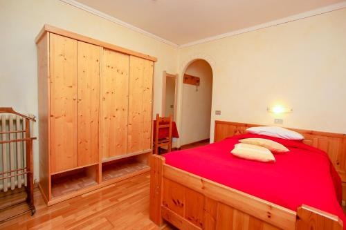 a bedroom with a large wooden bed with red sheets at Albergo Adele in Bormio