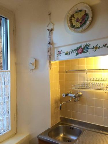 La salle de bains est pourvue d'un lavabo et d'un mur carrelé jaune. dans l'établissement Ad Palatium, à Cori