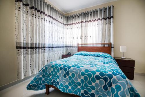 1 dormitorio con cama con edredón y cortinas azules en Hotel El Sol, en Piura