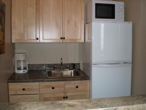 a kitchen with a sink and a white refrigerator at Spanish Bay Inn, CANADA in Sydney