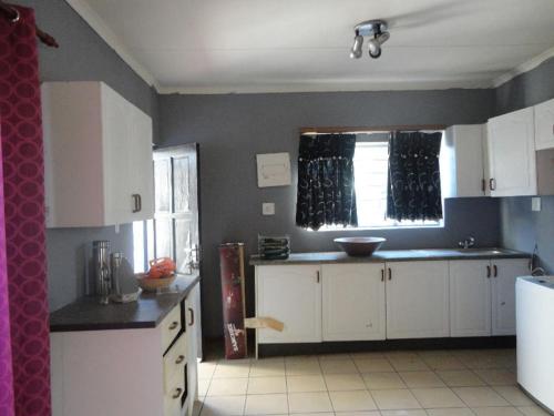 a kitchen with white cabinets and a window at East Cottage in Boksburg
