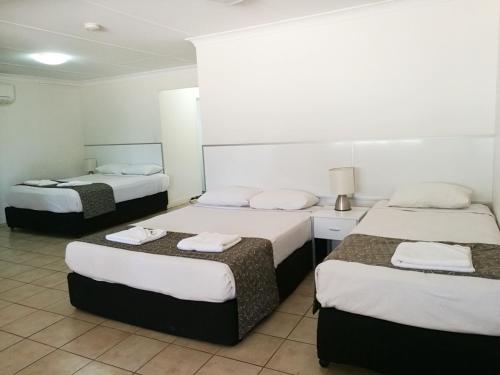 a hotel room with three beds with towels on them at Augathella Motel & Caravan Park in Augathella