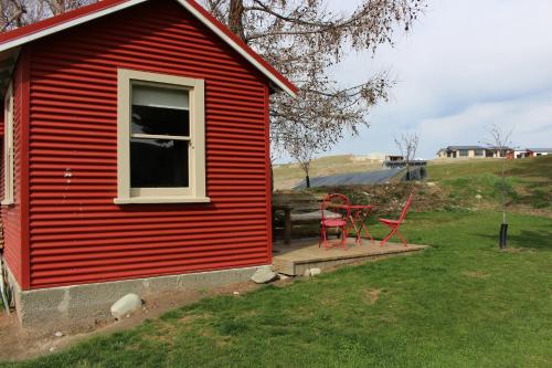a red house with two red chairs on a porch at The Red Hut in Lake Tekapo