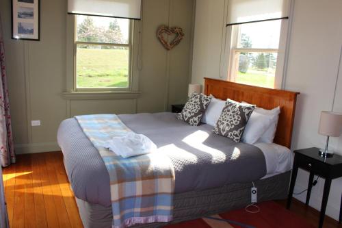 a bedroom with a large bed with two windows at The Red Hut in Lake Tekapo