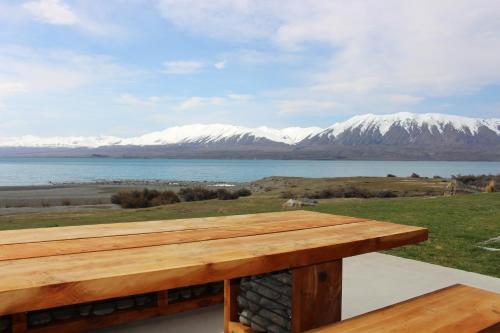 a wooden deck with a view of the water and mountains at Isolation Bay in Lake Tekapo