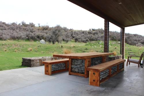 a picnic table and benches on a porch at Isolation Bay in Lake Tekapo