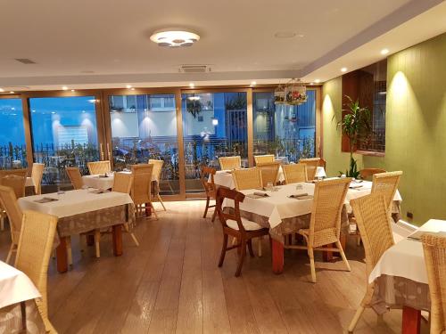 um restaurante com mesas e cadeiras brancas e janelas em HLL Hotel Lungolago Lecco em Lecco