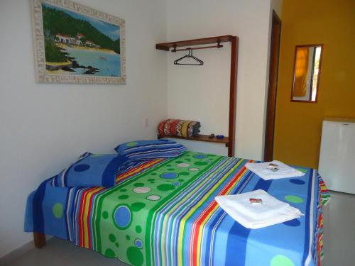een slaapkamer met een kleurrijk bed en 2 handdoeken bij Flores de Búzios Suítes in Búzios