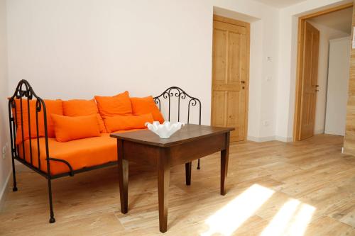an orange couch in a living room with a table at Cjase da Maestre in Raveo