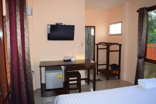 a room with a desk and a television and a bed at Bansuansiriwat in Ban Tak