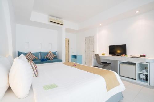 a white bedroom with a bed and a desk at Ocean Breeze Resort Khaolak in Khao Lak