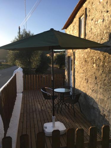 a table and chairs under an umbrella on a patio at Casa da Azenha Castellvm in Alcabideque