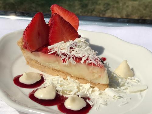 a piece of cheesecake with strawberries on a white plate at One Nature Nyaruswiga Serengeti in Banagi