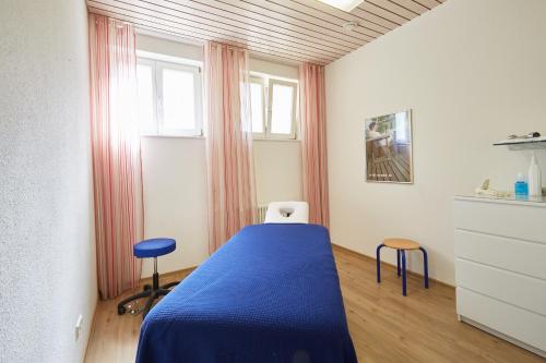 a bedroom with a blue bed and two stools at Ferien Residenz Bergfried in Hinterzarten
