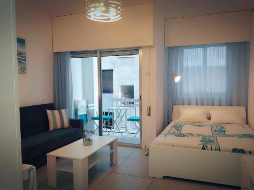 um pequeno quarto com uma cama e uma sala de estar em Billis Beach Apartment em Limassol