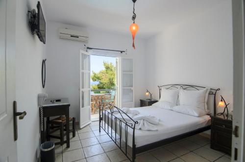 a bedroom with a bed and a balcony with a window at Yperia Hotel in Aegiali