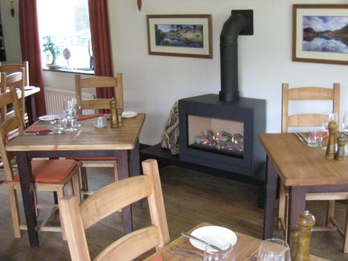 une salle à manger avec une cheminée, une table et des chaises dans l'établissement The Langstrath Country Inn, à Keswick