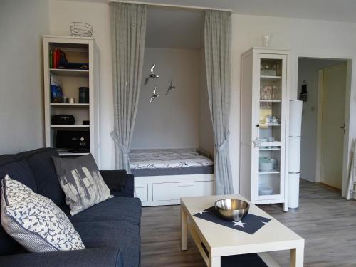 ein Wohnzimmer mit einem blauen Sofa und einem Tisch in der Unterkunft Ferienwohnung Möwe in Bremerhaven