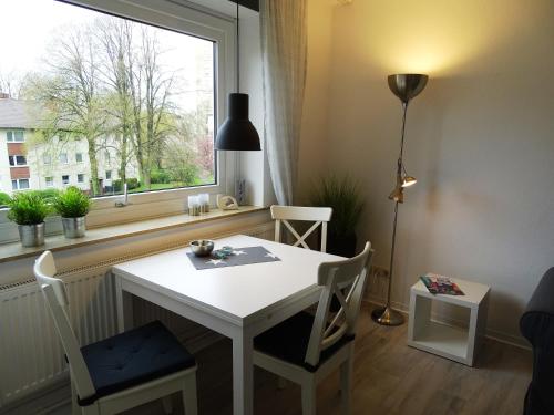 einen weißen Tisch und Stühle in einem Zimmer mit Fenster in der Unterkunft Ferienwohnung Möwe in Bremerhaven