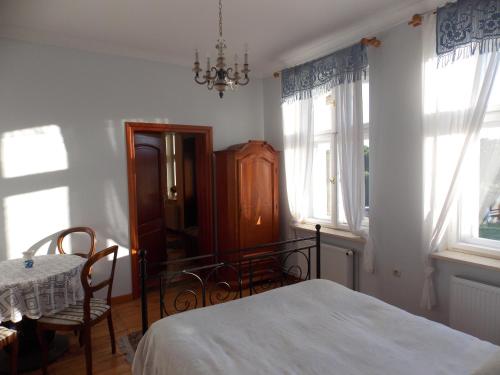 a bedroom with a bed and a table and windows at Dom Gościnny Ogłuszka in Pilec