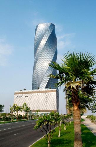 a tall building with a palm tree in front of it at Wyndham Grand Manama in Manama