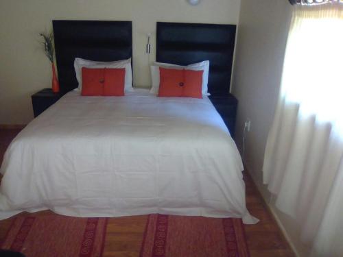 a bedroom with a large white bed with red pillows at LightStone Guesthouse in Centurion