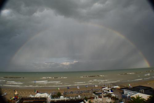 a rainbow over a beach with a crowd of people at Hotel Rosa Meublé in Porto San Giorgio