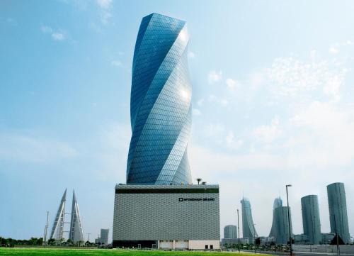 ويندهام جراند المنامة في المنامة: مبنى زجاجي طويل مع مدينة في الخلفية