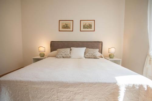 a bedroom with a large white bed with two lamps at Italianflat - Palazzo Zeiner in Verona