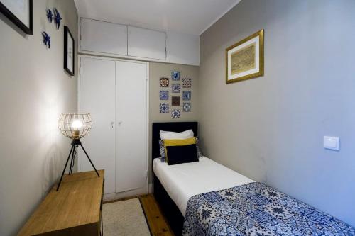 a small bedroom with a bed and a lamp at Ola Lisbon - Principe Real III in Lisbon