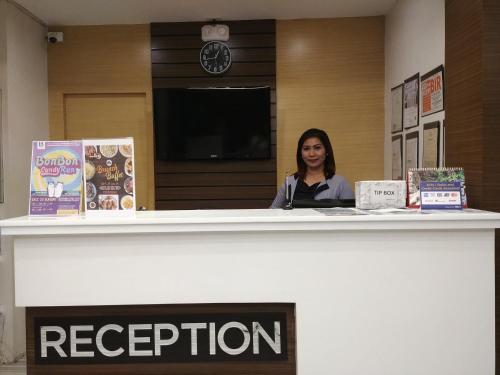 a woman sitting at a reception counter in a library at Bed and Bath Serviced Suites in Iloilo City