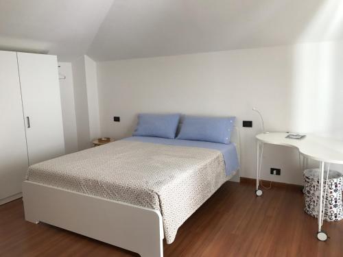 a white bedroom with a bed and a table at Appartamento Pedrotti in Arco