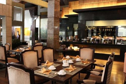 ein Restaurant mit einem langen Holztisch und Stühlen in der Unterkunft Crown Victoria Hotel Tulungagung in Tulungagung