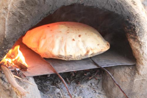 a bread cooking over a fire in a oven at Tahla Garden in Tahla