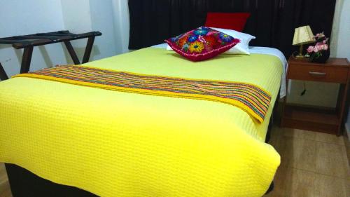 a yellow bed with a pillow on top of it at Hostal Mica in Abancay