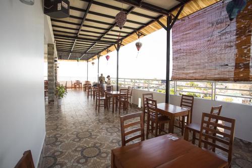 a restaurant with wooden tables and chairs and windows at Phu Hong Hotel in Phu Quoc