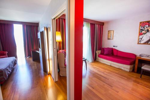a bedroom and a living room with a red couch at Cefalù Sea Palace in Cefalù