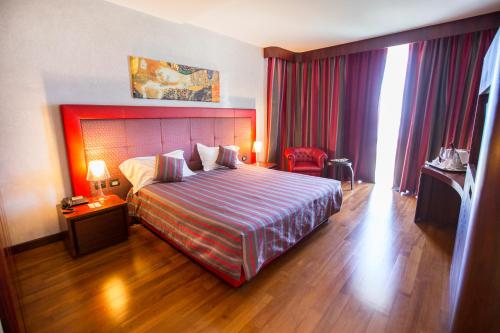 a hotel room with a large bed and red curtains at Cefalù Sea Palace in Cefalù