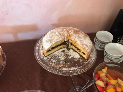 a cake on a plate on a table with a bowl of fruit at Rosy And Roby in Gasponi