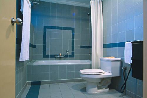 a blue tiled bathroom with a toilet and a tub at The Maple Suite in Kuala Lumpur