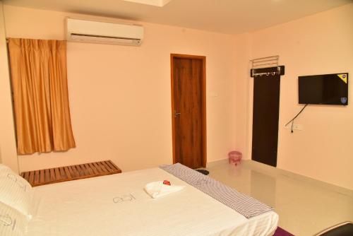 a hotel room with a bed and a television at Ananda Residency in Kumbakonam