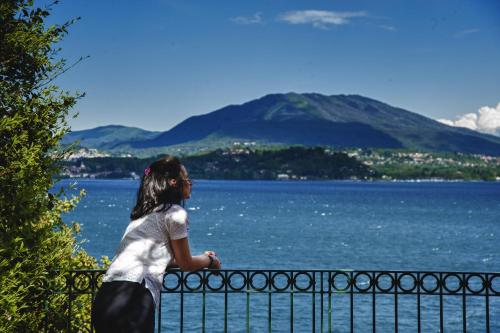 a woman standing on a fence overlooking a body of water at Relais Casali della Cisterna in Belgirate