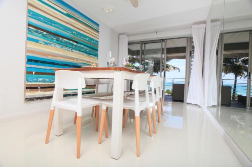 a dining room with a white table and chairs at Paradise Beach Luxury Beachfront Apartment Pointe d'Esny in Pointe d'Esny