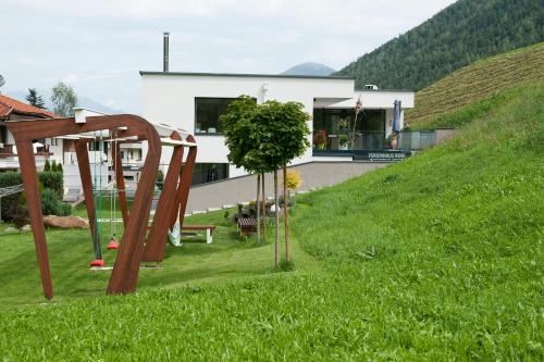 a house on a hill with a playground in the grass at Ferienwohnung Robi in Fulpmes