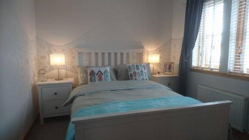 a bedroom with a large bed with two lamps at Sea Esta in Anstruther